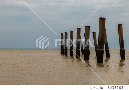 The leaning pillars of the old Pier looking toward beach on a sunny day. 84335034