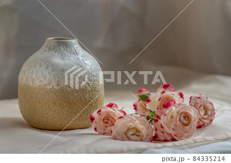 White and Yellow handmade ceramic vase with Bouquet of flower on Blush textured table cloth. 84335214