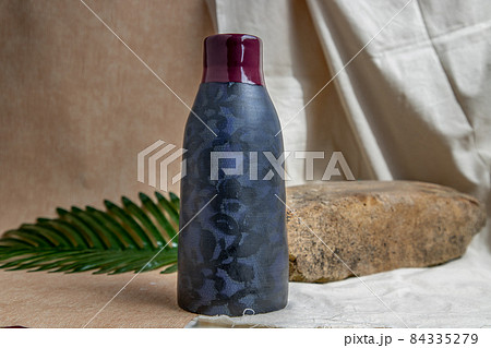 Blue and Crimson handmade ceramic vase on white textured table cloth. Blue and Crimson handmade ceramic vase on white textured table cloth. 84335279