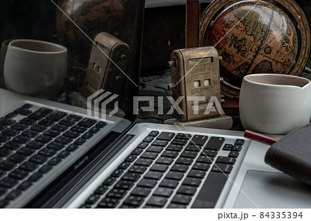 Workplace side view with laptop screen, keyboard, globe, desktop calendar, coffee mug and notebook with pencil at office workplace. Workplace side view with laptop screen, keyboard, globe, desktop calendar, coffee mug and notebook with pencil at office workplace. 84335394