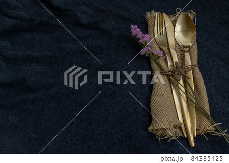 A set of bronze cutlery, spoon, fork and knife black background. 84335425