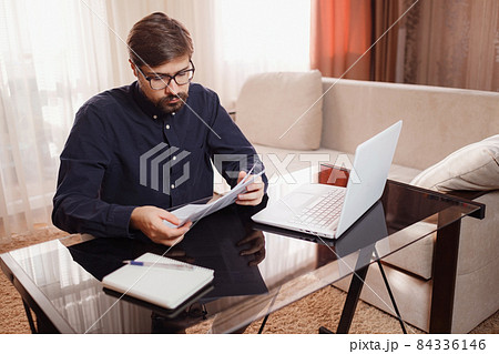 Entrepreneur works with a laptop and keeps a document in a home office 84336146