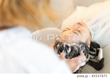 シャンプー台でシャンプーをする美容師 84337875