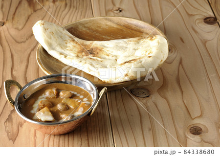 鶏肉や落花生など沢山の具材が入っているマッサマンカレーとナン 84338680