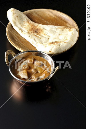 鶏肉や落花生など沢山の具材が入っているマッサマンカレーとナンを黒背景で撮影 84339109