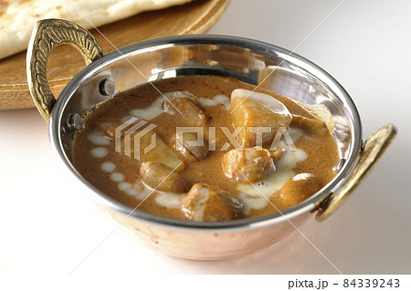 鶏肉や落花生など沢山の具材が入っているマッサマンカレーとナンを白背景で撮影 84339243