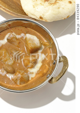 鶏肉や落花生など沢山の具材が入っているマッサマンカレーとナンを白背景で俯瞰撮影 84339290