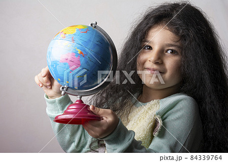 Little girl portrait holding a globe in hand and spin it Little girl portrait holding a globe in hand and spin it 84339764