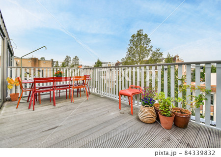 Delightful veranda with bright red wooden chairs and table Delightful veranda with bright red wooden chairs and table 84339832