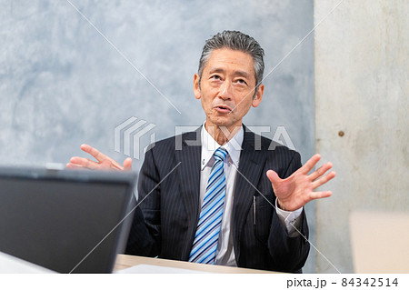 スーツで意見を述べる経営者 84342514