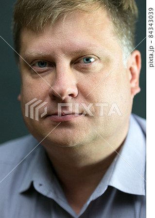 Portrait of a serious adult male blond 40 years old with a blue shirt on a black background 84343039