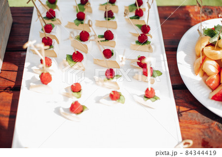 a lot of small cheescakes with raspberries on them 84344419