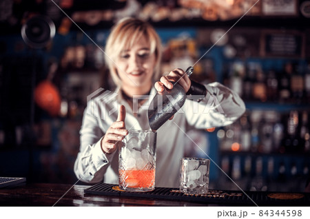 Portrait of girl barman places the finishing touches on a drink in the bar 84344598