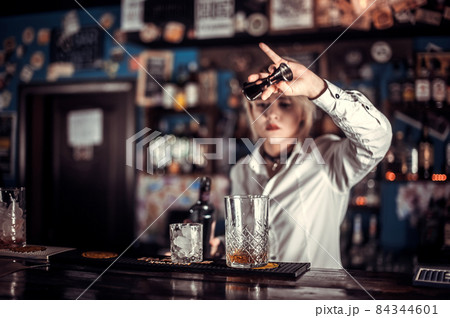 Professional woman bartending makes a show creating a cocktail behind bar 84344601
