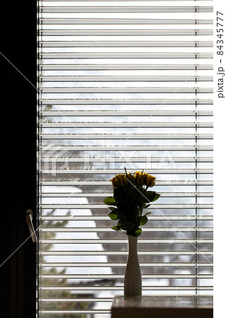 Dirty glass door. White ceramic vase with yellow rose on the table not in focus Dirty glass door. White ceramic vase with yellow rose on the table not in focus 84345777