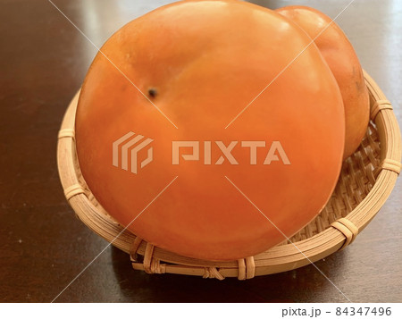 テーブルの上の籠に盛られた柿　写真素材 84347496