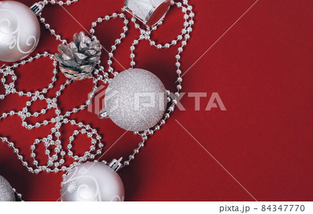 Silver baubles of Christmas decoration on a red background. Christmas balls, pine cones and new year's beads for the tree. Flat lay. 84347770