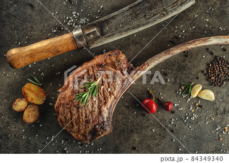 Grilled beef tomahawk steak fillet with ingredients and herbs on black board, product image for restaurant Grilled beef tomahawk steak fillet with ingredients and herbs on black board, product image for restaurant 84349340