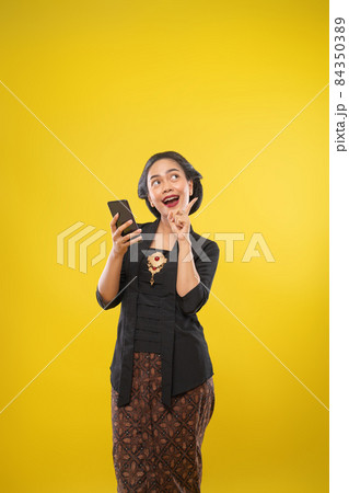 woman with traditional Javanese clothes excited looking up woman with traditional Javanese clothes excited looking up 84350389