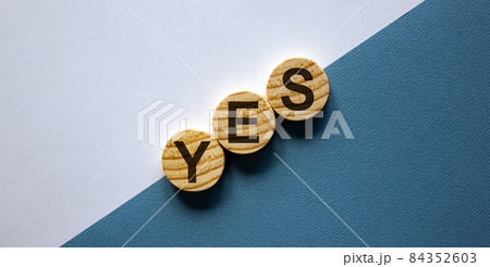 Wood circles with word 'yes' stacking as step stair on paper white and blue background, copy space. Business concept. Wood circles with word 'yes' stacking as step stair on paper white and blue background, copy space. Business concept. 84352603