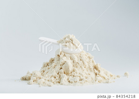 A mountain of soy protein isolate in powder with a measuring spoon on a white background. A mountain of soy protein isolate in powder with a measuring spoon on a white background. 84354218