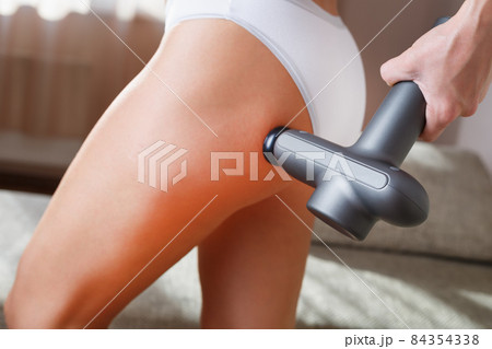 Self-massage of the female buttock with a percussion massage gun at home. Self-massage of the female buttock with a percussion massage gun at home. 84354338