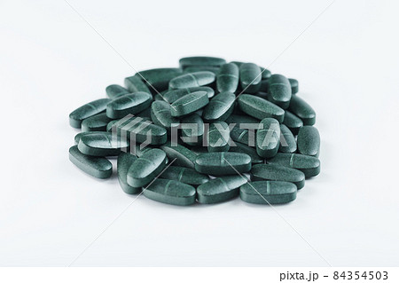 Green tablets with vitamins and spirulina for men on a white background. Green tablets with vitamins and spirulina for men on a white background. 84354503