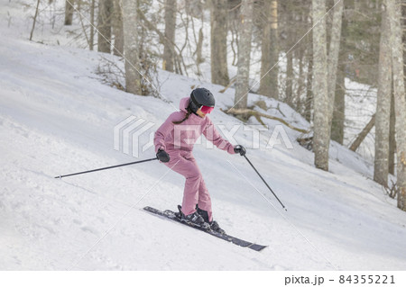 Alpine Skiing Downhill. Woman on ski going downhill having fun on the slopes on a snowy day - Winter sport and activities. Cool ski clothing, goggles and helment. Good skier 84355221