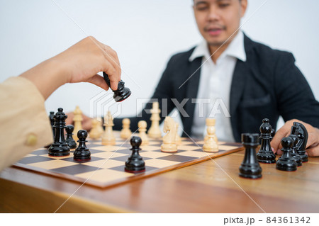 Hands holding horse while playing chess against background of man Hands holding horse while playing chess against background of man 84361342