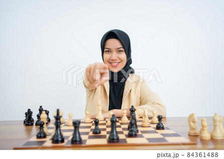 Hijab woman with finger pointing while sitting playing chess 84361488