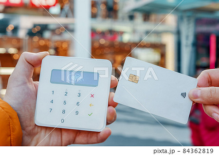 Crop unrecognizable client with plastic card making NFC payment on POS terminal in urban shop in city street Crop unrecognizable client with plastic card making NFC payment on POS terminal in urban shop in city street 84362819