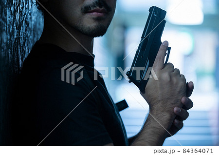 犯罪のイメージに使えそうな目元の切れた写真と銃のクローズアップ 犯罪のイメージに使えそうな目元の切れた写真と銃のクローズアップ 84364071