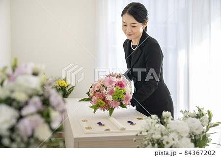 棺上花束を供えるミドルの女性 84367202