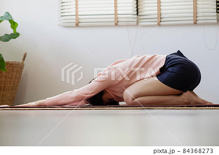 Asian woman working out in sportswear while doing yoga, seated in Child exercise, Balasana stance. Asian woman working out in sportswear while doing yoga, seated in Child exercise, Balasana stance. 84368273