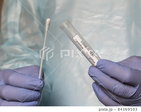 Hands in medical gloves holding an oral sample swab and a test tube for covid test 84369503