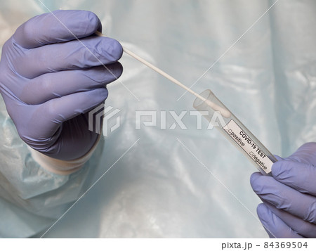 Hands in medical gloves holding an oral sample swab and a test tube for covid test Hands in medical gloves holding an oral sample swab and a test tube for covid test 84369504