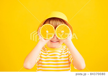 Happy child holding slices of orange fruit like sunglasses 84370080