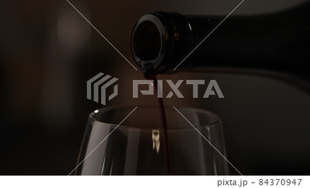 pour red wine into wineglass closeup 84370947