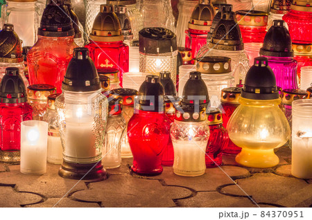 Burning grave candles in the cemetery at night. 84370951