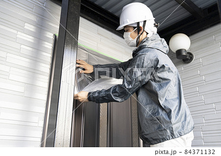 戸建て住宅の玄関の養生をする塗装職人 84371132