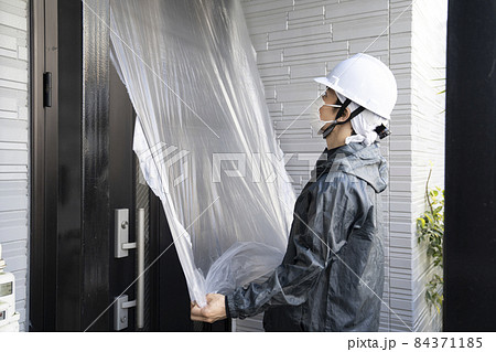 戸建て住宅の玄関の養生をする塗装職人 84371185