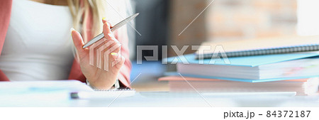 Business woman holding silver ballpoint pen at table with folders closeup 84372187