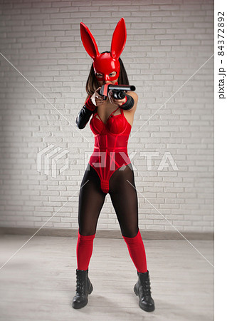 asian girl in a red rabbit mask and a sexy red bodysuit with a shotgun in the image of a superhero 84372892