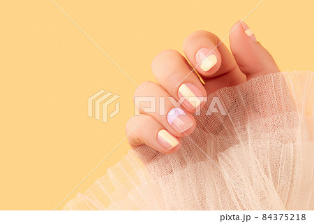 Beautiful females hand with manicure on yellow background. Trendy minimal spring summer nail design 84375218