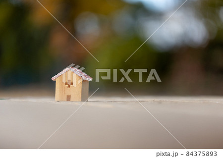 モザイクガラスの屋根の木製の小さなおうち（秋の色づいた樹背景） 84375893