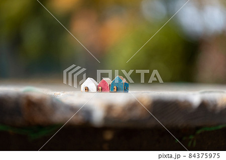 木製の小さな可愛い3軒のおうち(秋の色づいた樹背景) 木製の小さな可愛い3軒のおうち(秋の色づいた樹背景) 84375975
