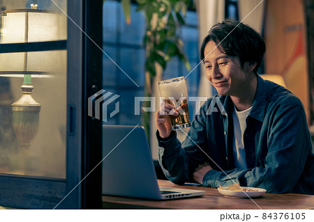 夜ビールを飲みながらzoomで話をする若い男性 夜ビールを飲みながらzoomで話をする若い男性 84376105