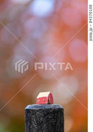 木製の小さな可愛い赤色のおうち(秋の色づいた樹背景) 木製の小さな可愛い赤色のおうち(秋の色づいた樹背景) 84376106