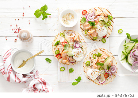 Spicy tacos with grilled salmon, vegetables, ricotta cheese, chili and fresh mint 84376752