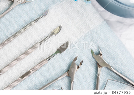 Manicure tools are laid out on a white-blue striped towel, studio photo 84377959